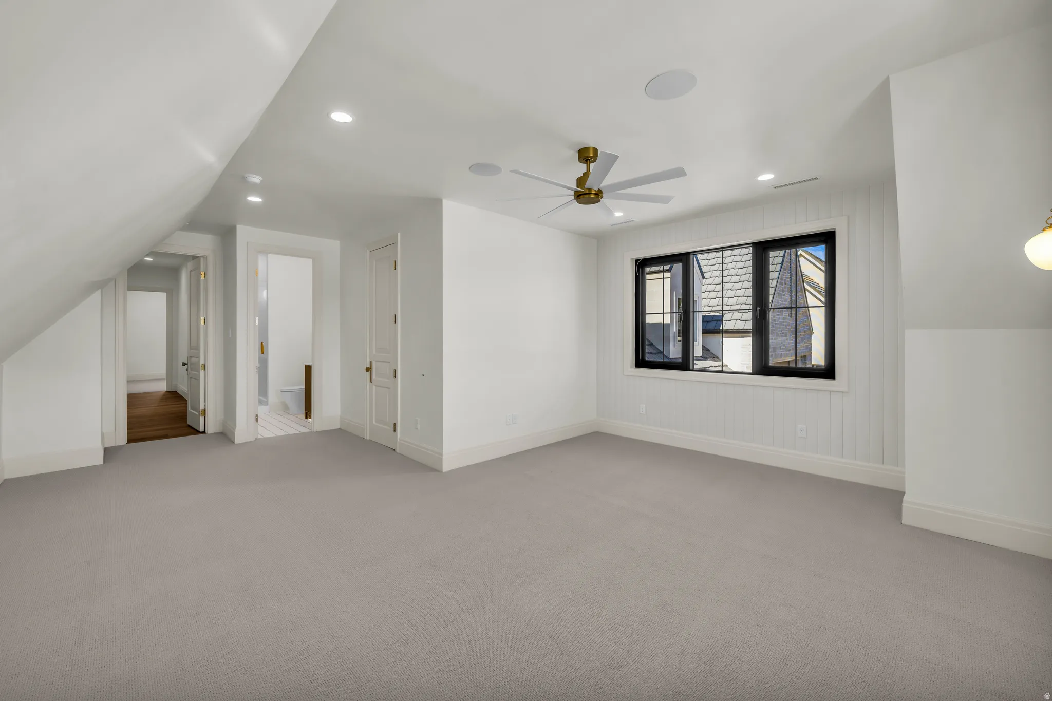Spacious room featuring vaulted ceilings, recessed lighting, and light gray carpeting
