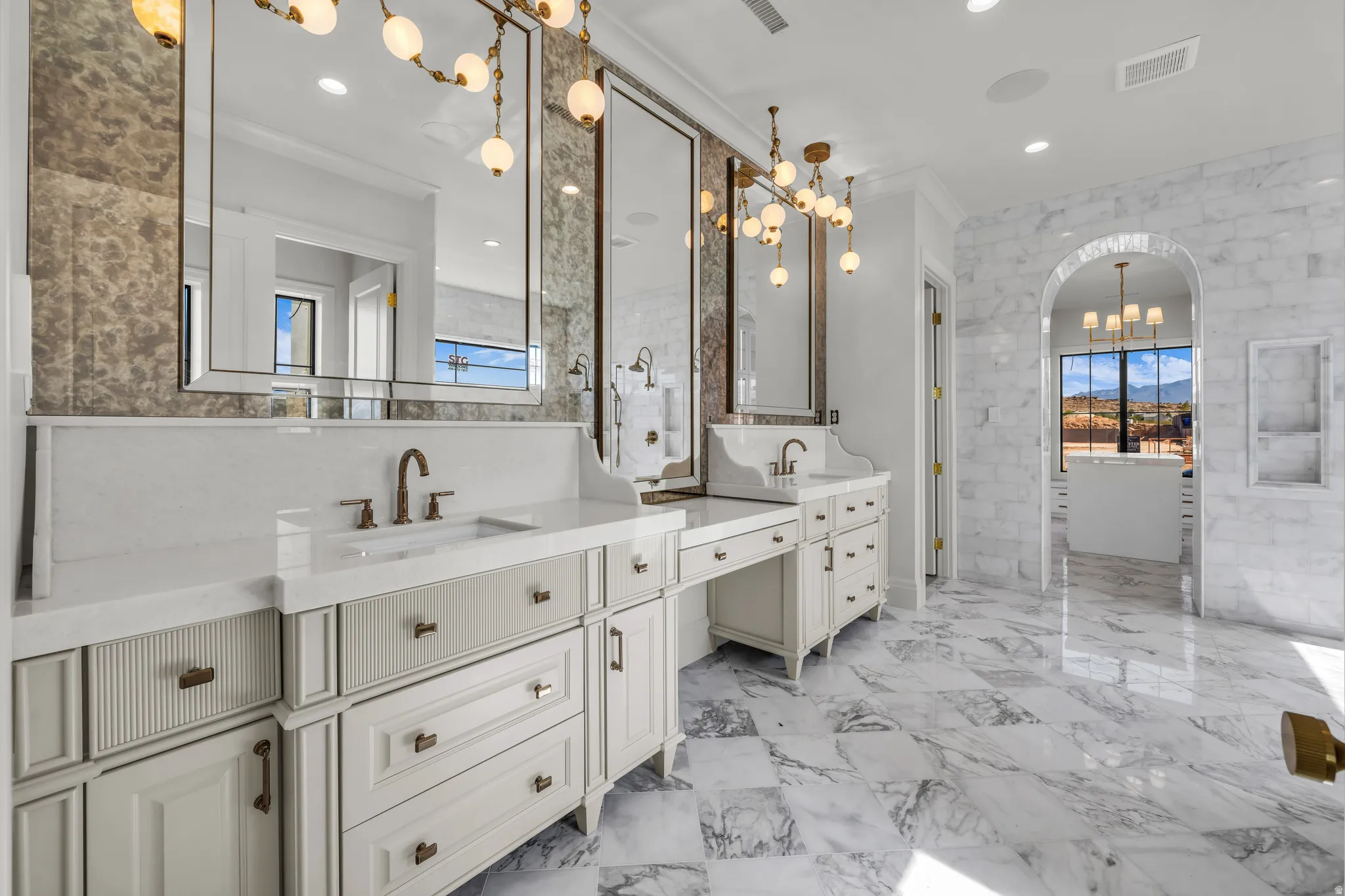 Spacious bathroom featuring dual vanities with integrated sinks, white countertops, and bronze-finish faucets