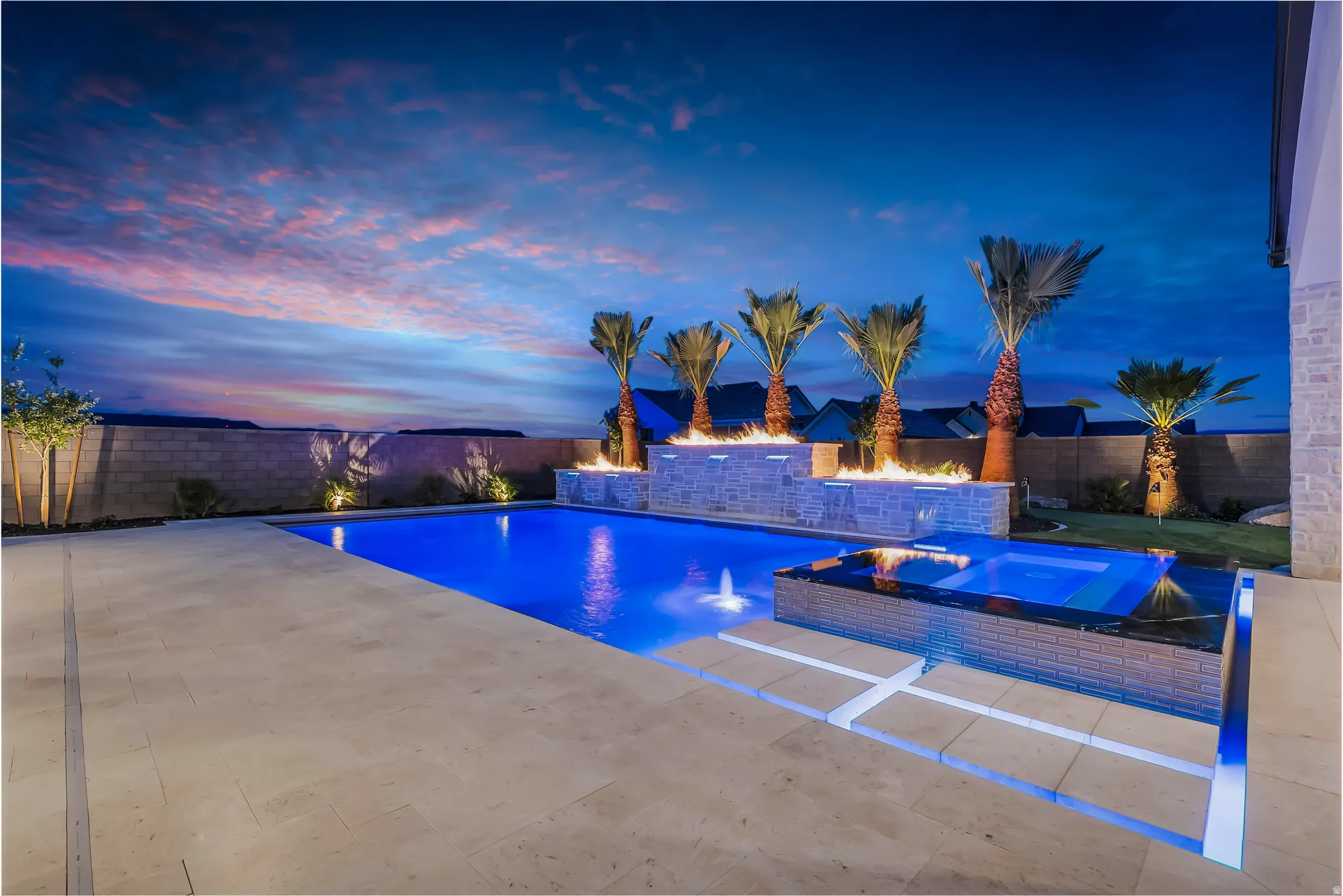Resort-style backyard featuring a rectangular swimming pool, integrated spa, fire features, and mature palm trees
