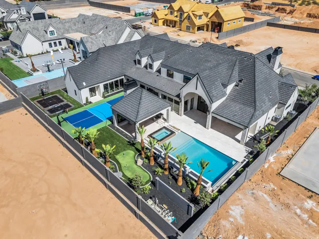 Expansive backyard oasis featuring a swimming pool, integrated spa, covered patio, sport court, putting green, and mature palm trees