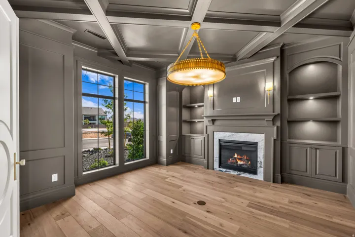 Coffered ceiling with a central chandelier, complemented by recessed lighting and wall sconces