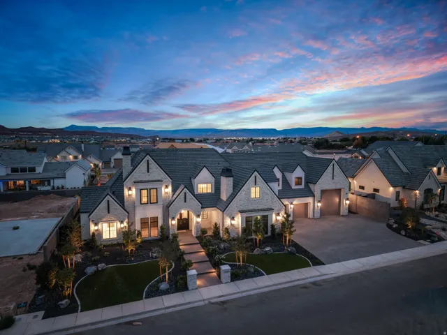 Grand residence featuring a stone and stucco exterior, prominent gabled rooflines, an inviting entryway, a paved driveway, and established front landscaping