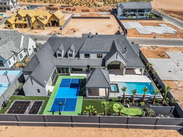 Rear exterior featuring a sport court, putting green, two in-ground trampolines, swimming pool with integrated spa, and an outdoor covered patio