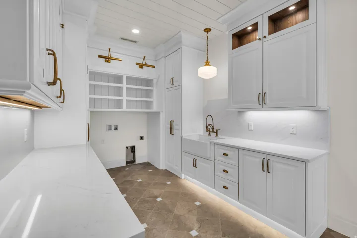 Utility room featuring white cabinetry, quartz countertops, a farmhouse sink, and under-cabinet lighting