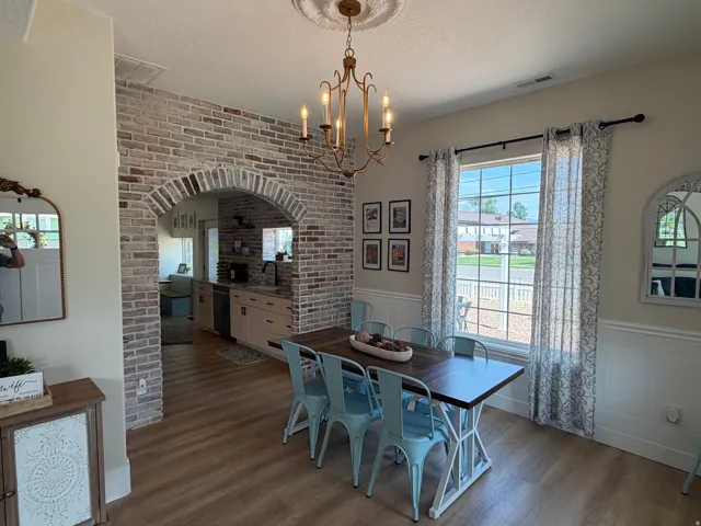 Dining area featuring a decorative chandelier with a ceiling medallion, wood-finish flooring, and wainscoting