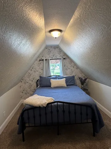 Attic room featuring sloped ceilings, textured wall finishes, and a single window