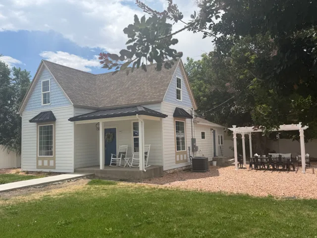 White siding exterior featuring a blue door, covered front porch, and a dormer with blue shingles
