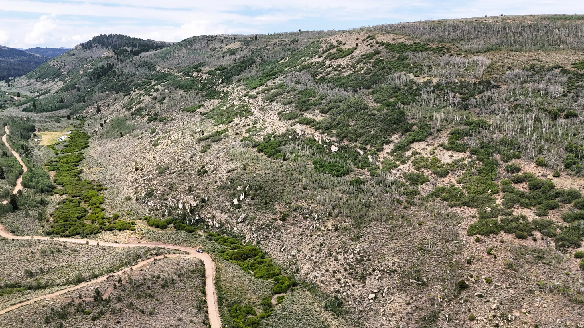 Expansive mountain landscape featuring varied terrain, natural rock formations, and multiple winding dirt roads