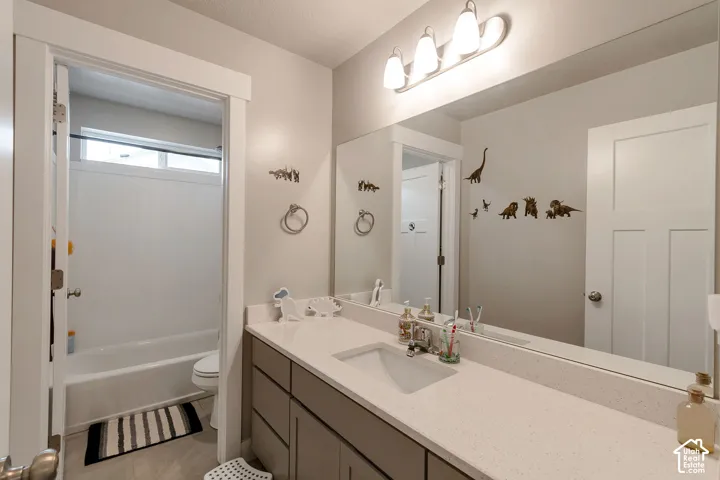 Bathroom featuring a single vanity with stone-finish countertop, under-mount sink, and extensive mirror
