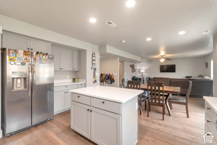 Open-concept kitchen featuring wood-finish flooring, light gray cabinetry, and a central island with quartz  countertop
