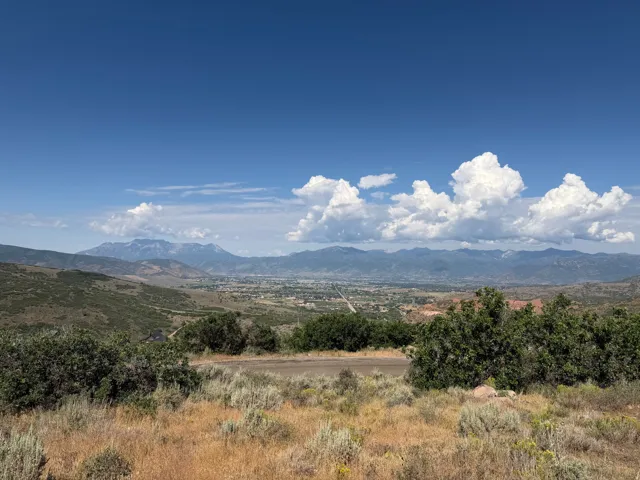Expansive landscape featuring distant mountains, a valley settlement, and varied natural foliage