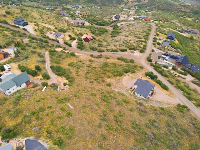 Expansive land parcel featuring natural shrubbery and varied topography, surrounded by existing residential structures