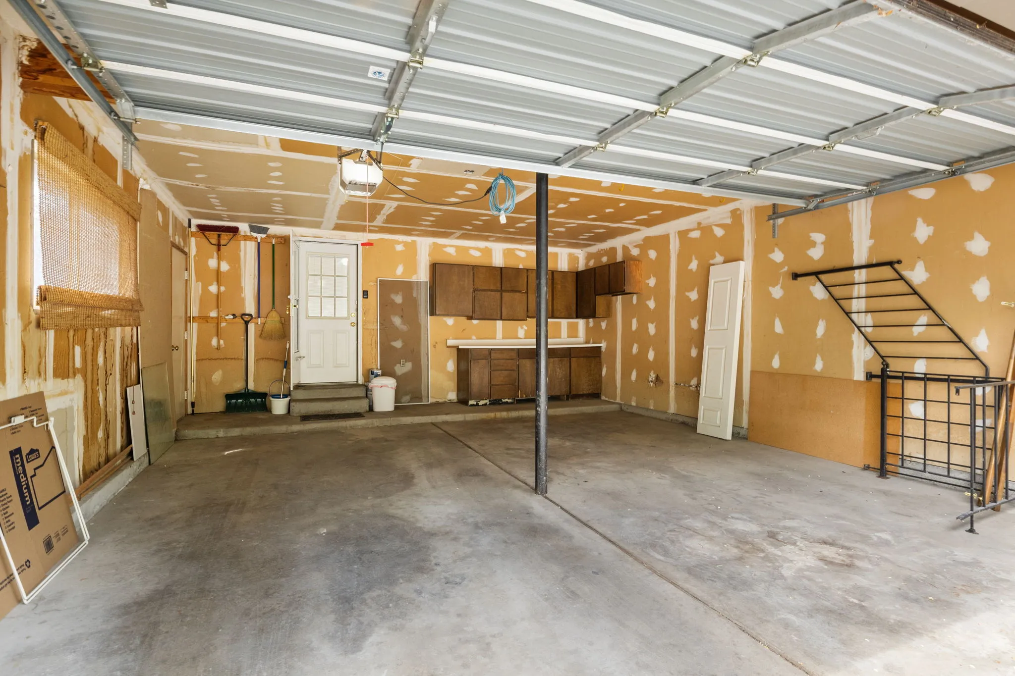 Spacious garage featuring a concrete floor, exposed ceiling joists, and a rear access door