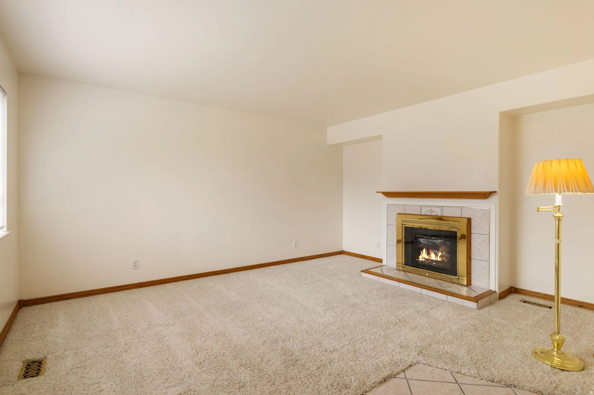 Living area featuring a fireplace with a brass-trimmed insert, light-colored tile surround, and a natural wood mantel