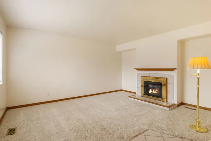Living area featuring a fireplace with a brass-trimmed insert, light-colored tile surround, and a natural wood mantel