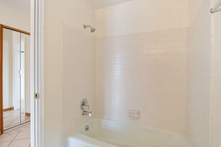Bathtub with white subway tile surround, chrome fixtures, and integrated soap dish