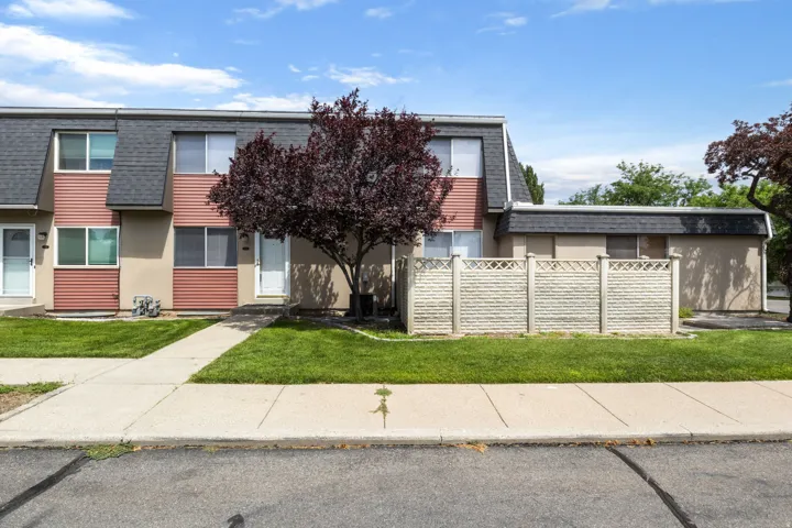 Multi-level townhome exterior featuring an asphalt shingle roof and tan stucco siding with red panel accents