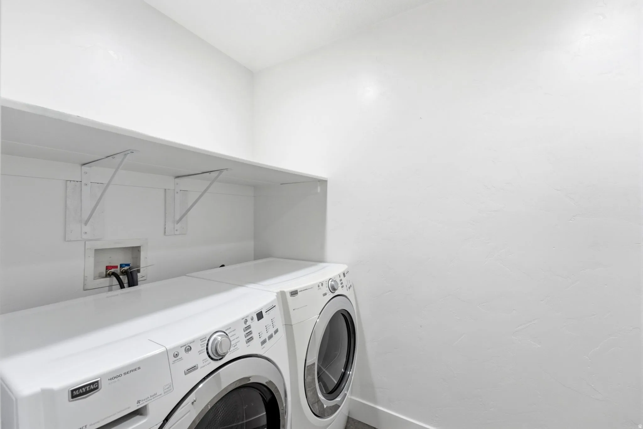 Dedicated laundry area featuring a wall-mounted shelf, appliance hookups, and light-colored walls