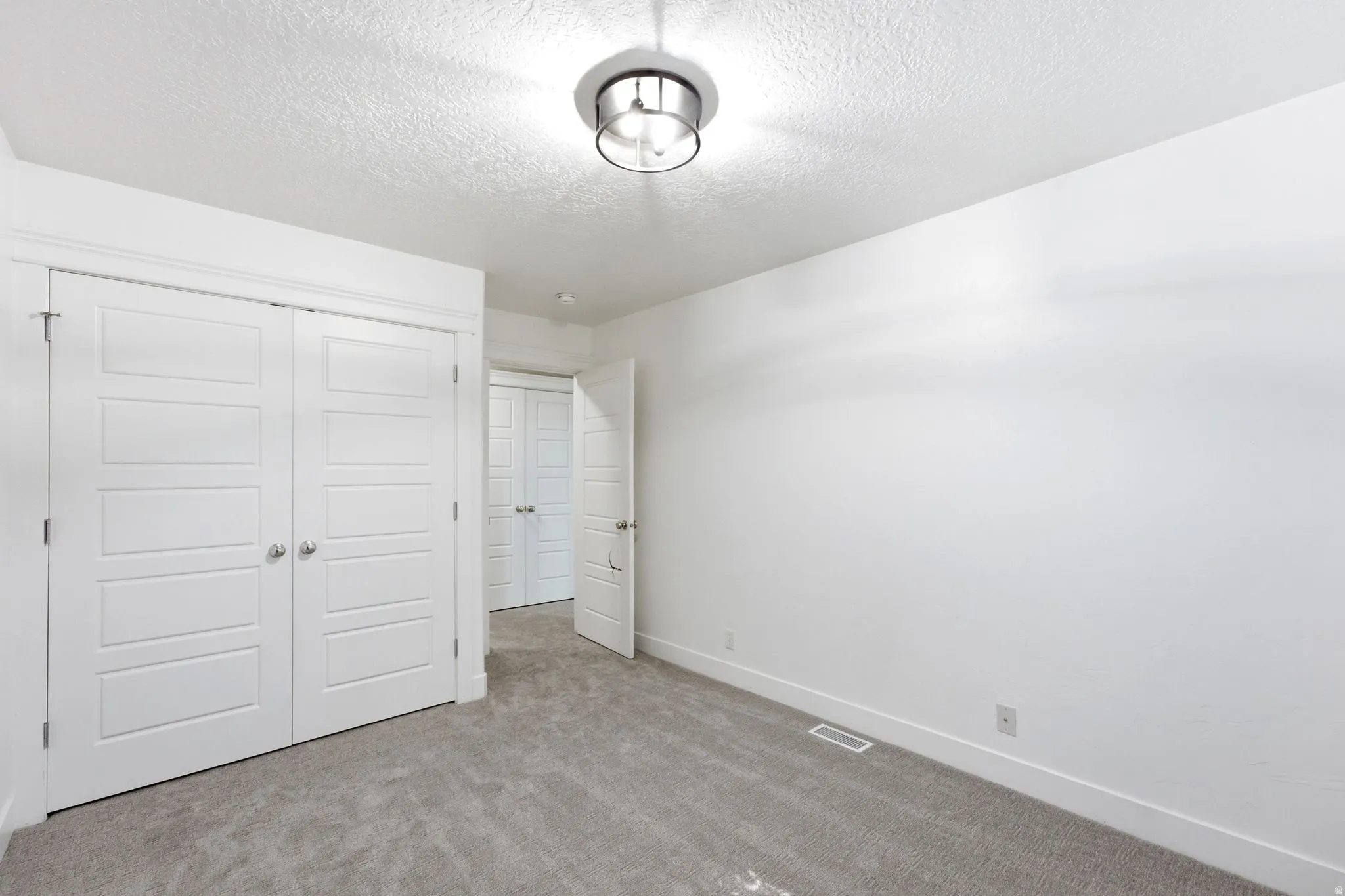 Bright interior space featuring light gray carpeting, light grey walls, and a contemporary semi-flush ceiling fixture