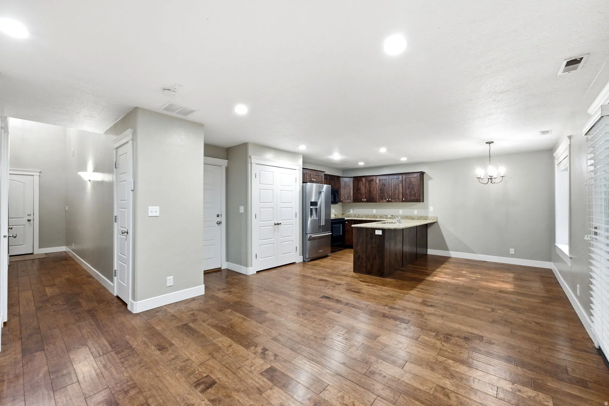 Expansive living area featuring warm wood-finish flooring, recessed lighting, and a neutral wall palette