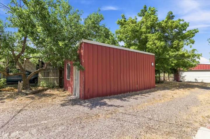 Red-sided outbuilding shed featuring a white trim roofline and a single window
