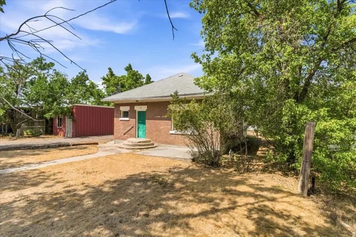 Brick exterior featuring a bright green front door and a concrete entry patio