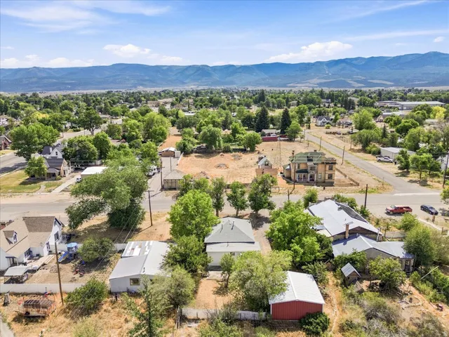 Expansive land parcel featuring multiple structures, mature trees, and mountainous scenery