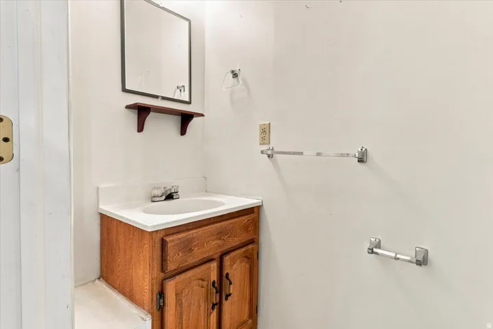 Bathroom vanity with wood-finish cabinetry, integrated sink, and laminate countertop