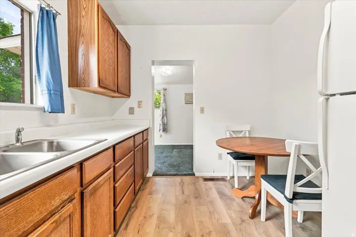 Efficient kitchen featuring wood cabinetry, white countertops, a stainless steel sink, and LVP flooring