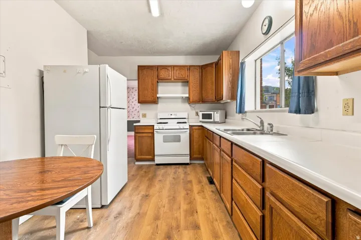 Kitchen featuring LVP flooring, white appliances, and a double basin sink