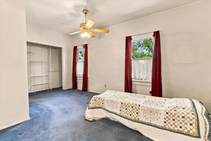 Room featuring wall-to-wall blue carpeting, two windows,  and ceiling fan