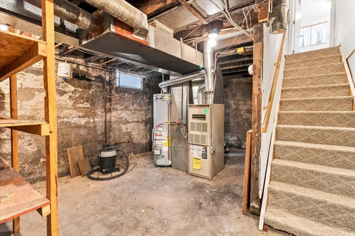 Basement utility area featuring a furnace, water heater, and exposed overhead ductwork