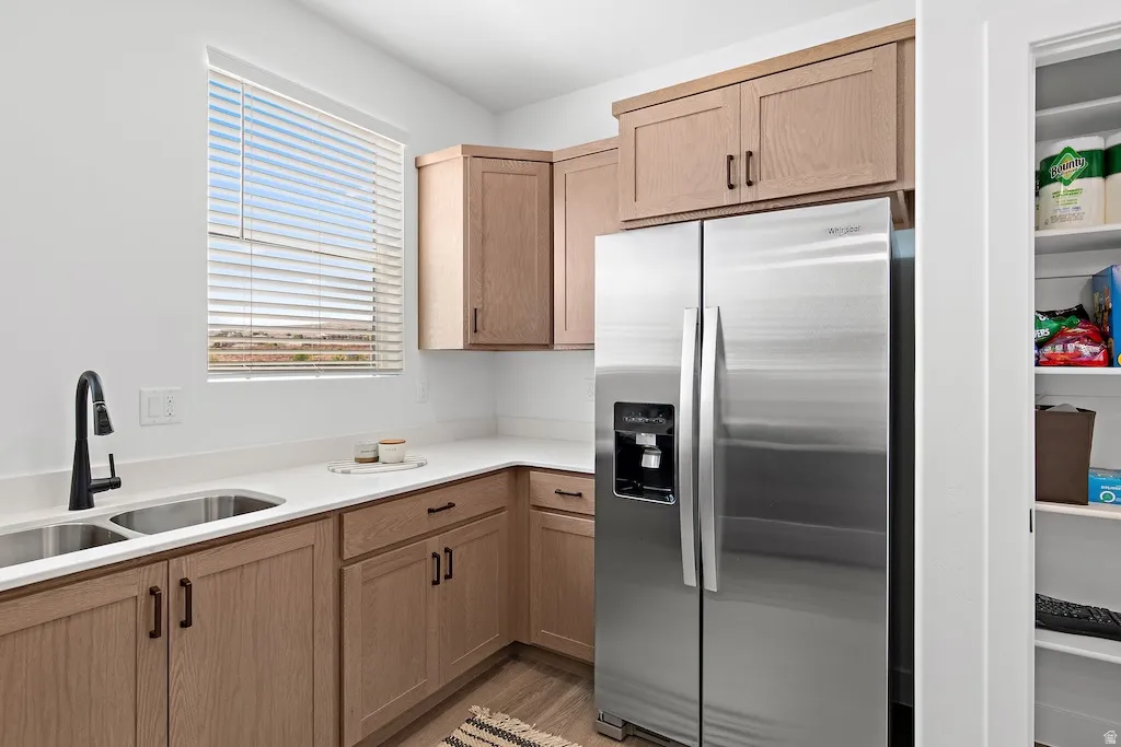 Modern kitchen featuring light wood-finish cabinetry, white countertops, and a dual stainless steel sink with a matte black faucet