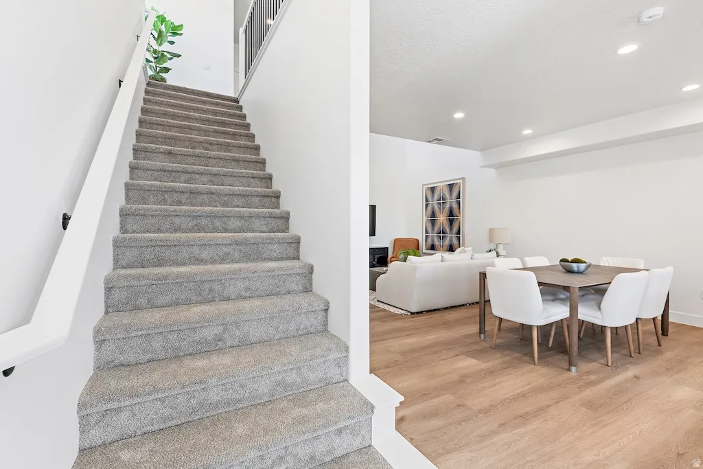Carpeted staircase with white handrail and black balusters