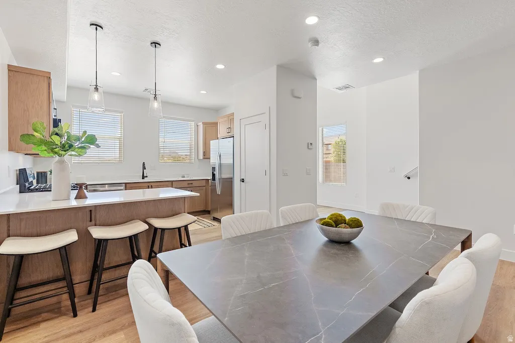 Open-concept kitchen and dining area featuring light wood-finish flooring, recessed lighting, and a kitchen island with seating