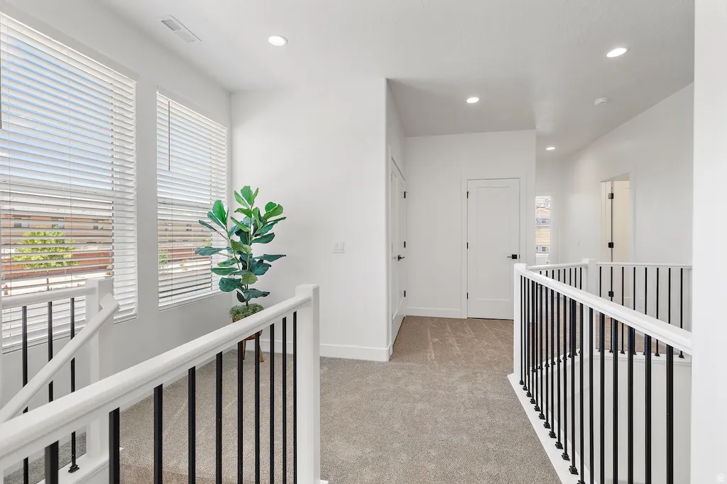 Upper-level hallway featuring a neutral carpet, white walls, and recessed lighting