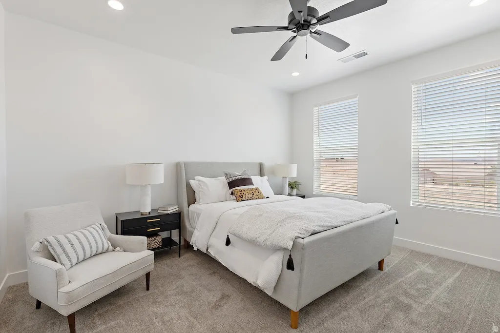 Bright interior room featuring neutral-toned carpet flooring, recessed lighting, and a ceiling fan
