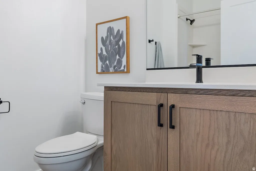 Bathroom vanity featuring wood-finish cabinetry with black hardware, a white countertop, and a black faucet