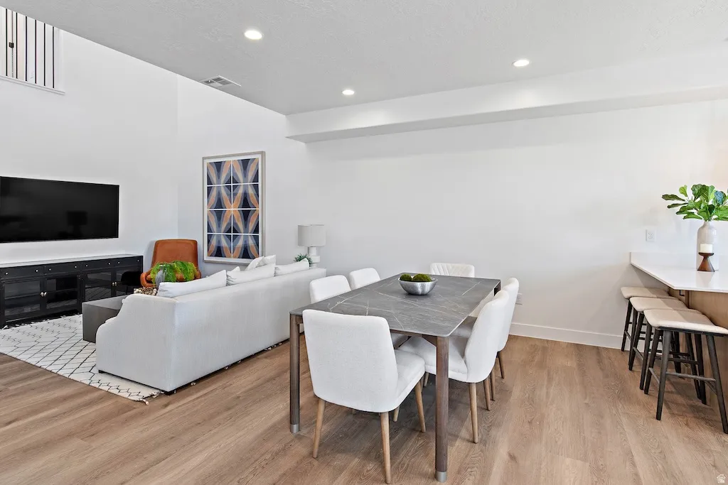 Open concept living space featuring wood-finish flooring throughout, recessed lighting, and a high ceiling