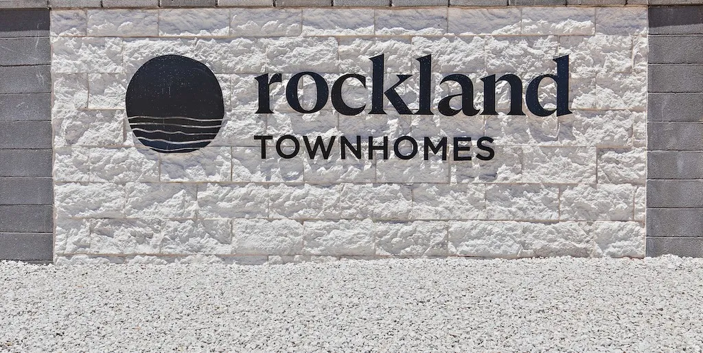 Rockland Townhomes signage featuring a white textured stone facade