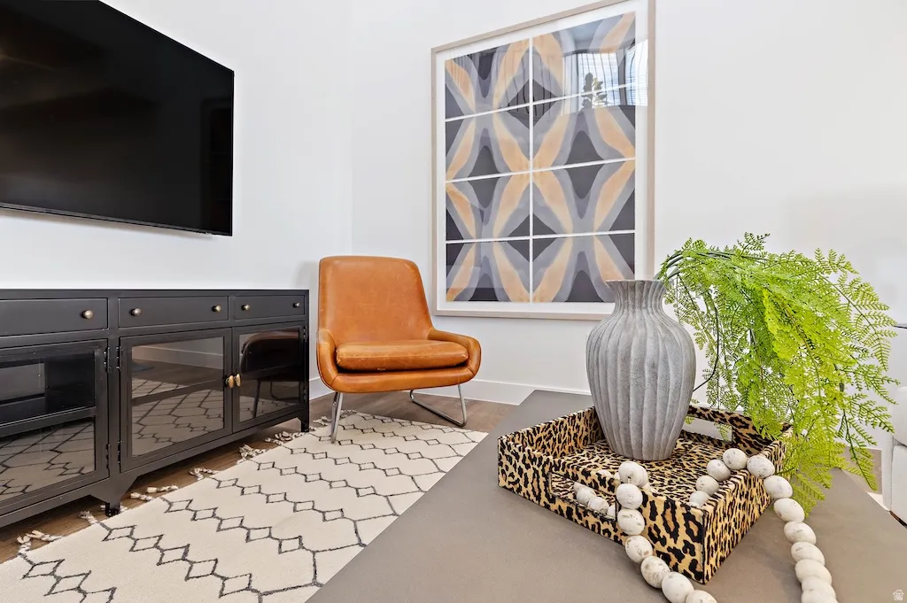 White wall with a large framed abstract artwork, wood-finish flooring, and a contemporary media console with glass panel doors