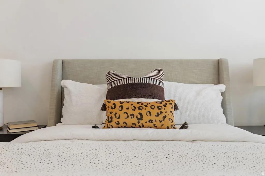 Upholstered wingback headboard with a neutral fabric finish, complemented by white wall paint and a dark-toned nightstand