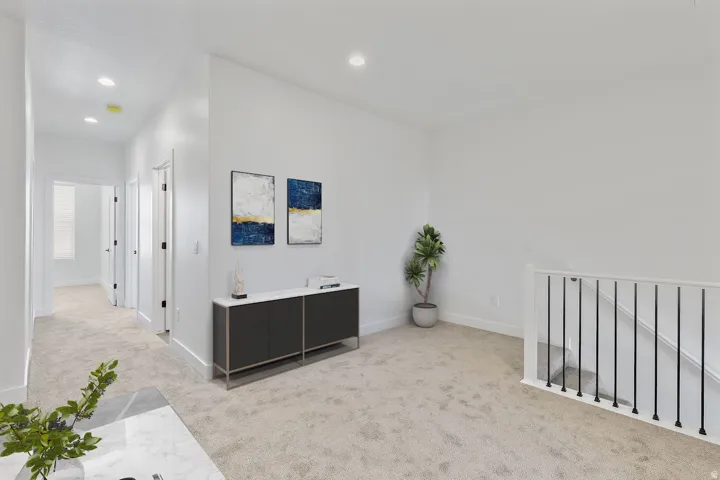 Upper-level hallway and open area with light-toned carpeting, recessed lighting, and white walls