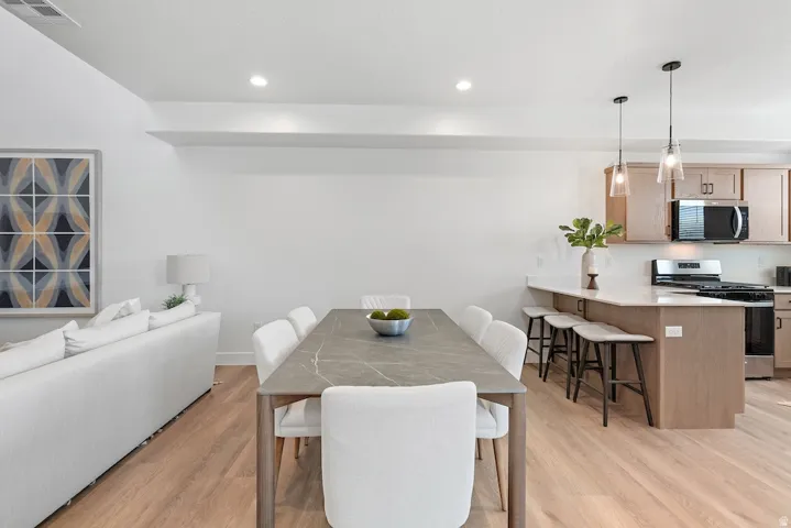 Open-concept living space featuring wood-finish flooring, recessed lighting, and a kitchen island with pendant lighting
