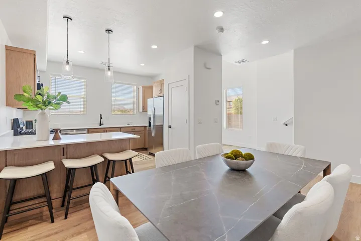 Open-concept kitchen and dining area featuring light wood-finish flooring, recessed lighting, and a kitchen island with seating