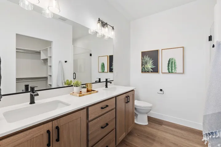 Dual vanity with wood-finish cabinetry, white countertops, and matte black fixtures