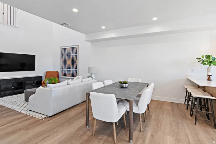 Open concept living space featuring wood-finish flooring throughout, recessed lighting, and a high ceiling