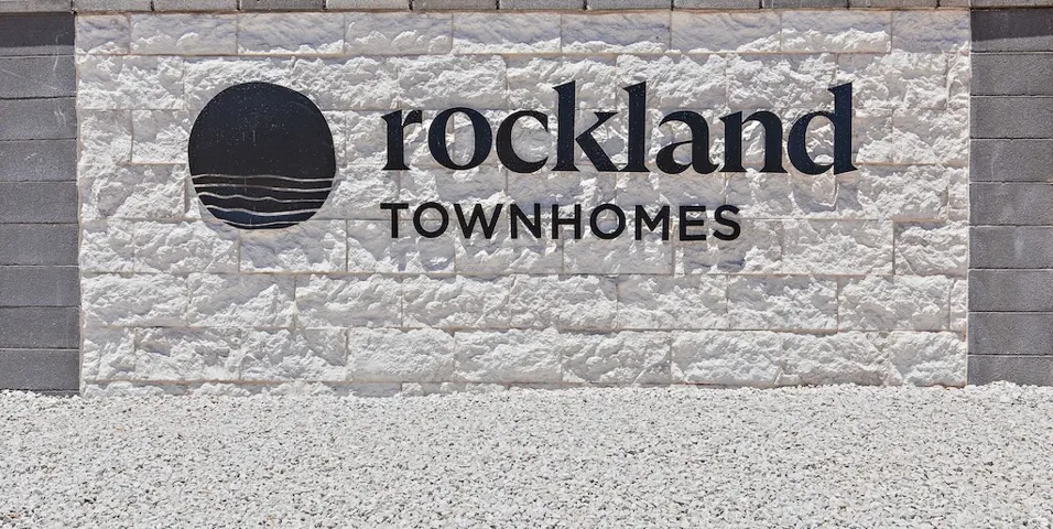 Rockland Townhomes signage featuring a white textured stone facade
