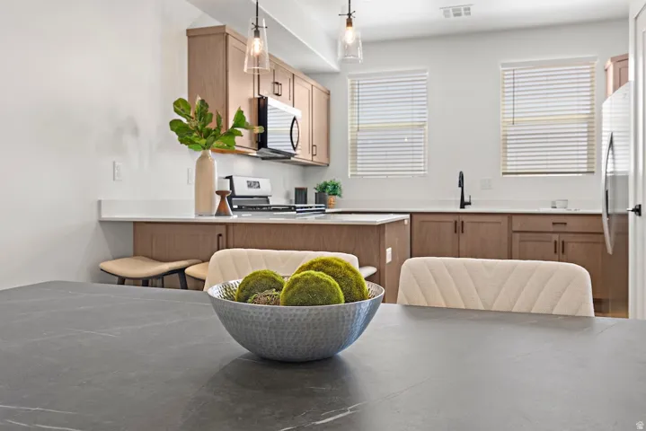 Kitchen featuring light wood-finish cabinetry, white countertops, and a stainless steel appliance suite including a built-in microwave and gas range