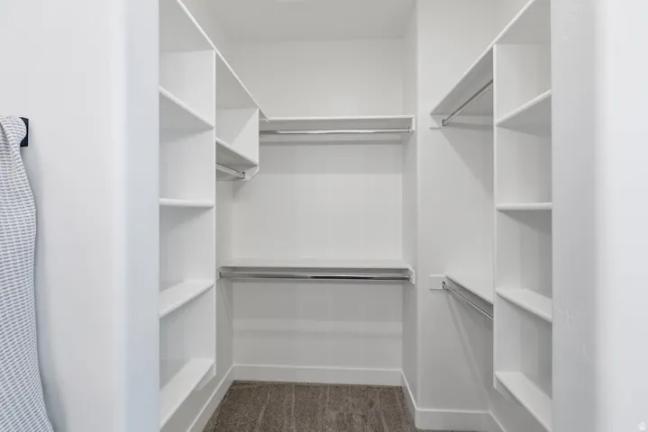 Walk-in closet featuring built-in shelving, multiple hanging rods, and wood-finish flooring